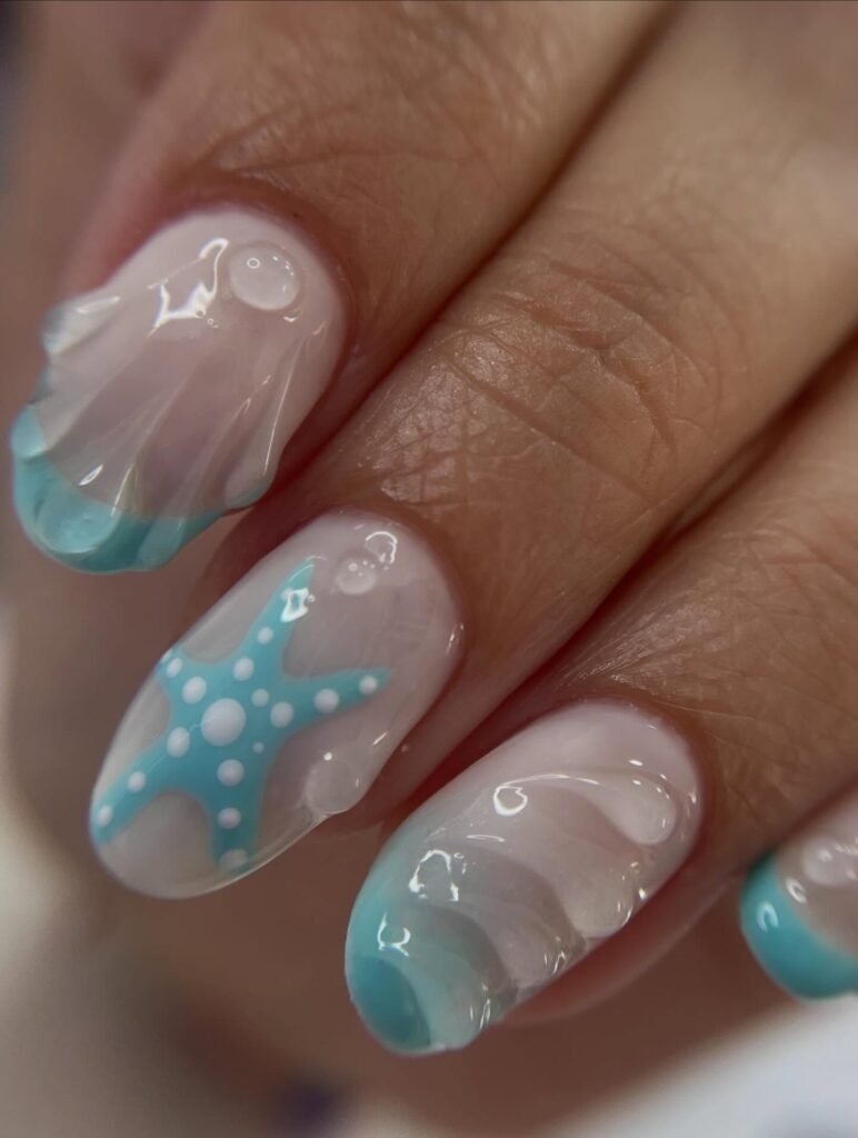 Close-up of nails with ocean-themed design featuring blue starfish, white waves, and glossy finish.