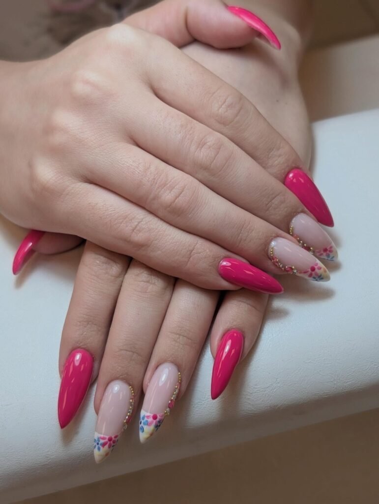 Bright pink and floral nail art design on manicured hands, showcasing creative and stylish nail inspiration.