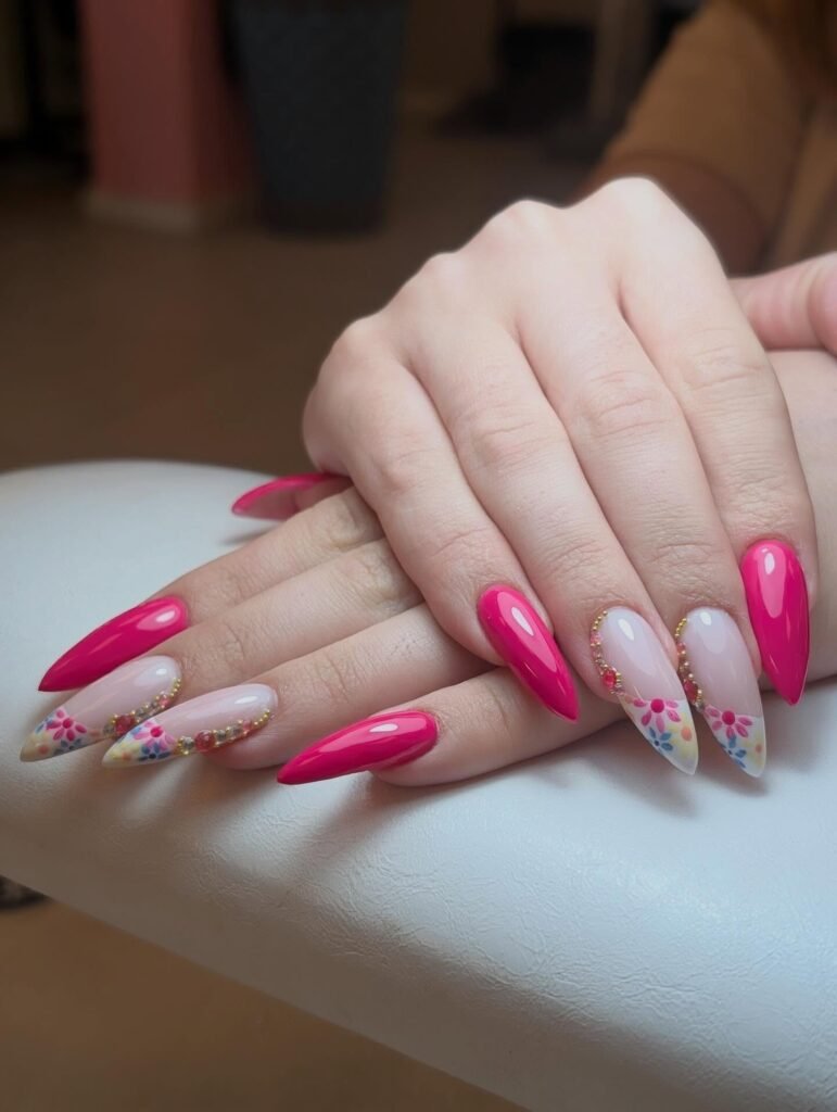 Bright pink and floral stiletto nails with intricate design on a white background. Perfect for a fashion-forward manicure.