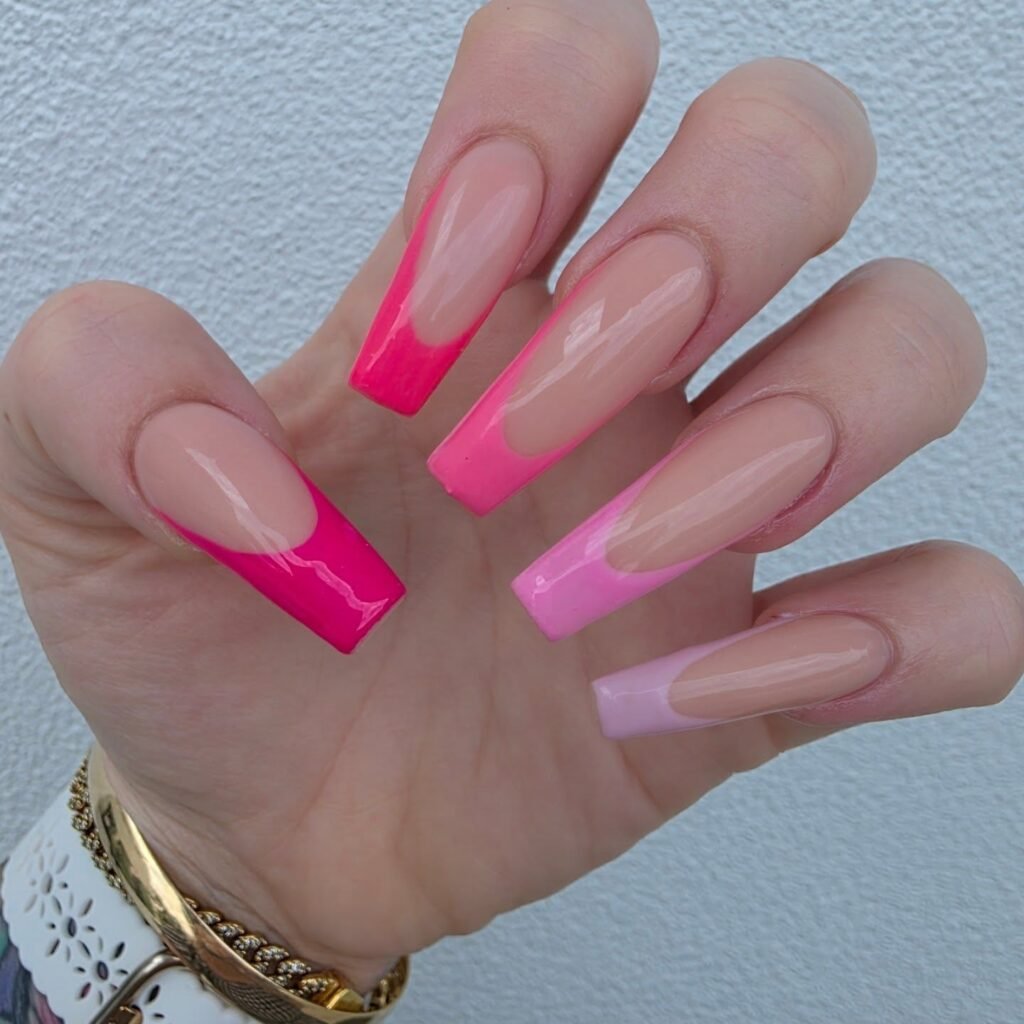 Hand with gradient pink coffin nails, showcasing modern nail art against a textured background.