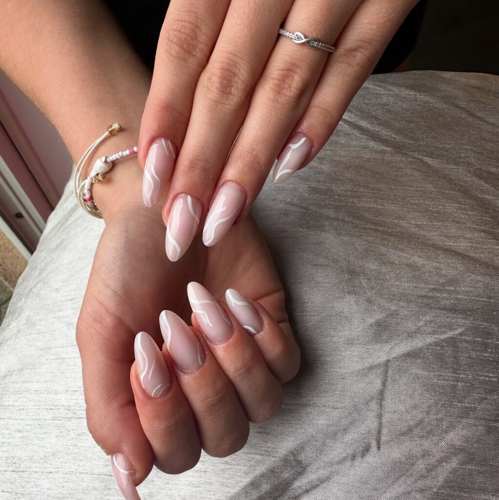 Elegant almond-shaped nails with a white swirl design, perfect for a minimalist nail art look.