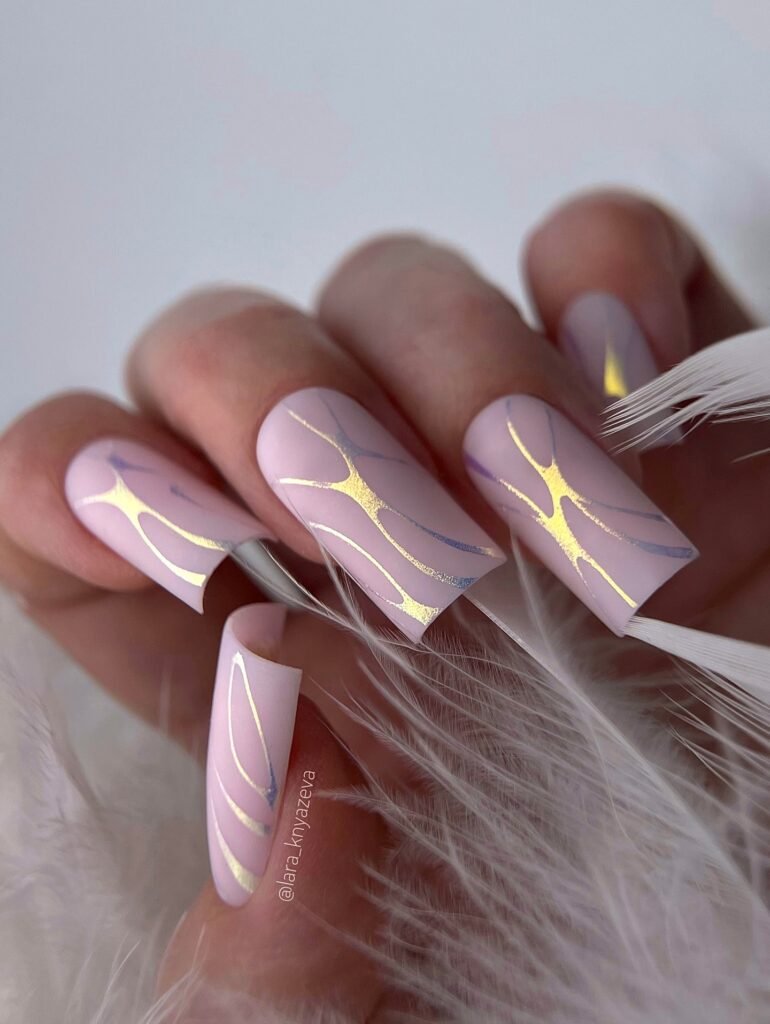 Elegant pink nails with abstract gold and silver line art, perfect for a stylish and sophisticated look.