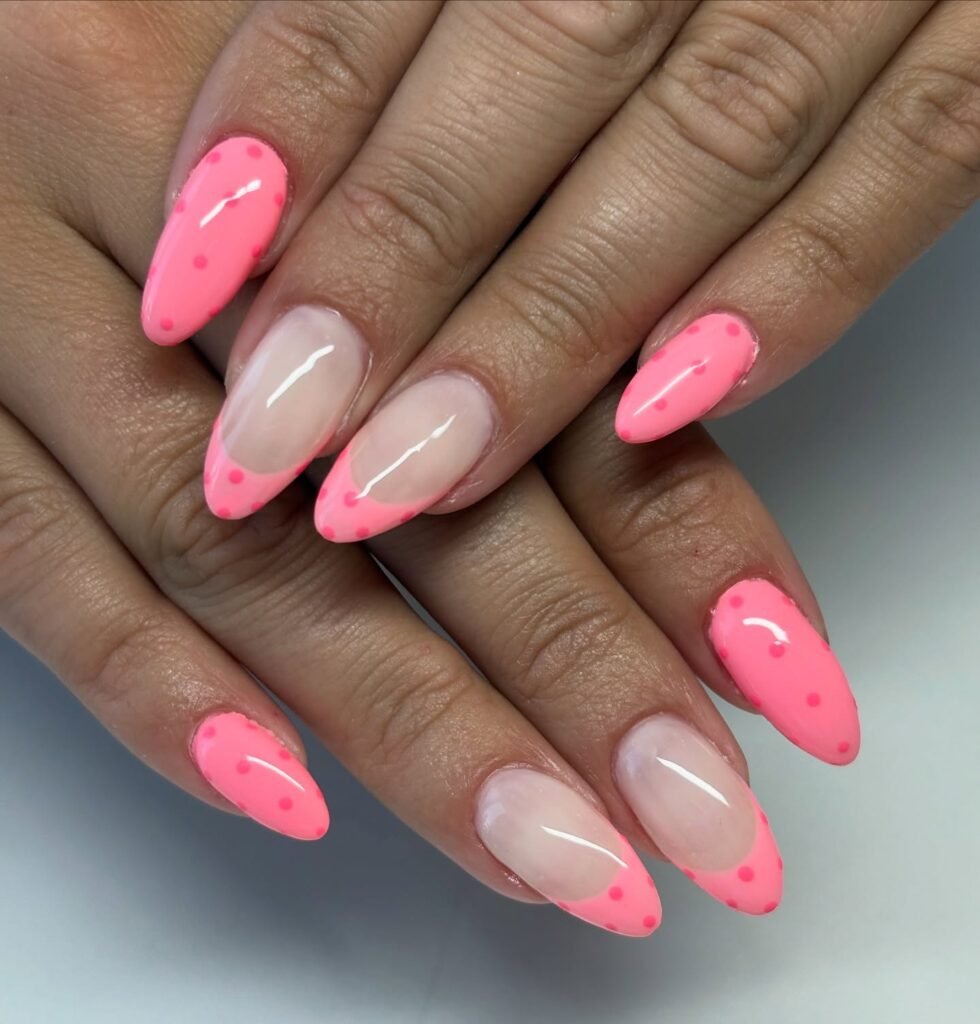 Bright pink polka dot nail art on almond-shaped nails for a trendy, eye-catching manicure.