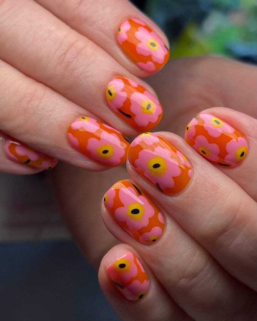 Colorful floral nail art with bright orange and pink flowers, perfect for a vibrant summer manicure design.