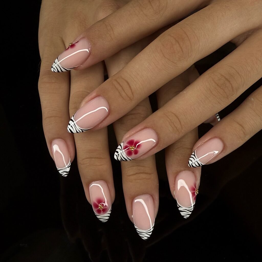 Elegant nail art with zebra stripes and red floral accents on almond-shaped nails, showcasing creative manicure design.