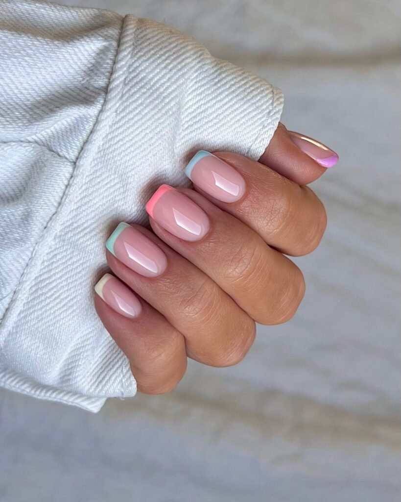Close-up of a hand with pastel French manicure, featuring multicolor tips. Perfect for a trendy nail art look.
