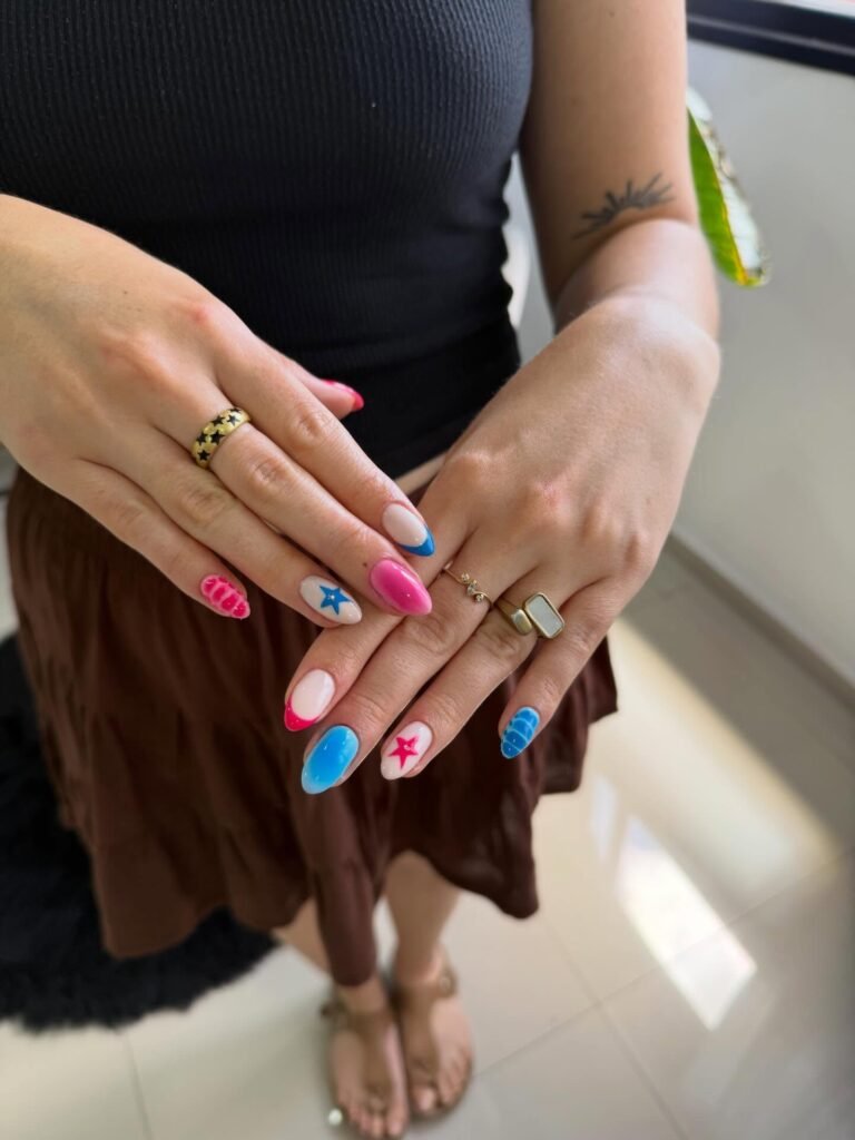 Colorful star and stripe nail art on manicured hands with gold rings. Fashionable and trendy nail design.
