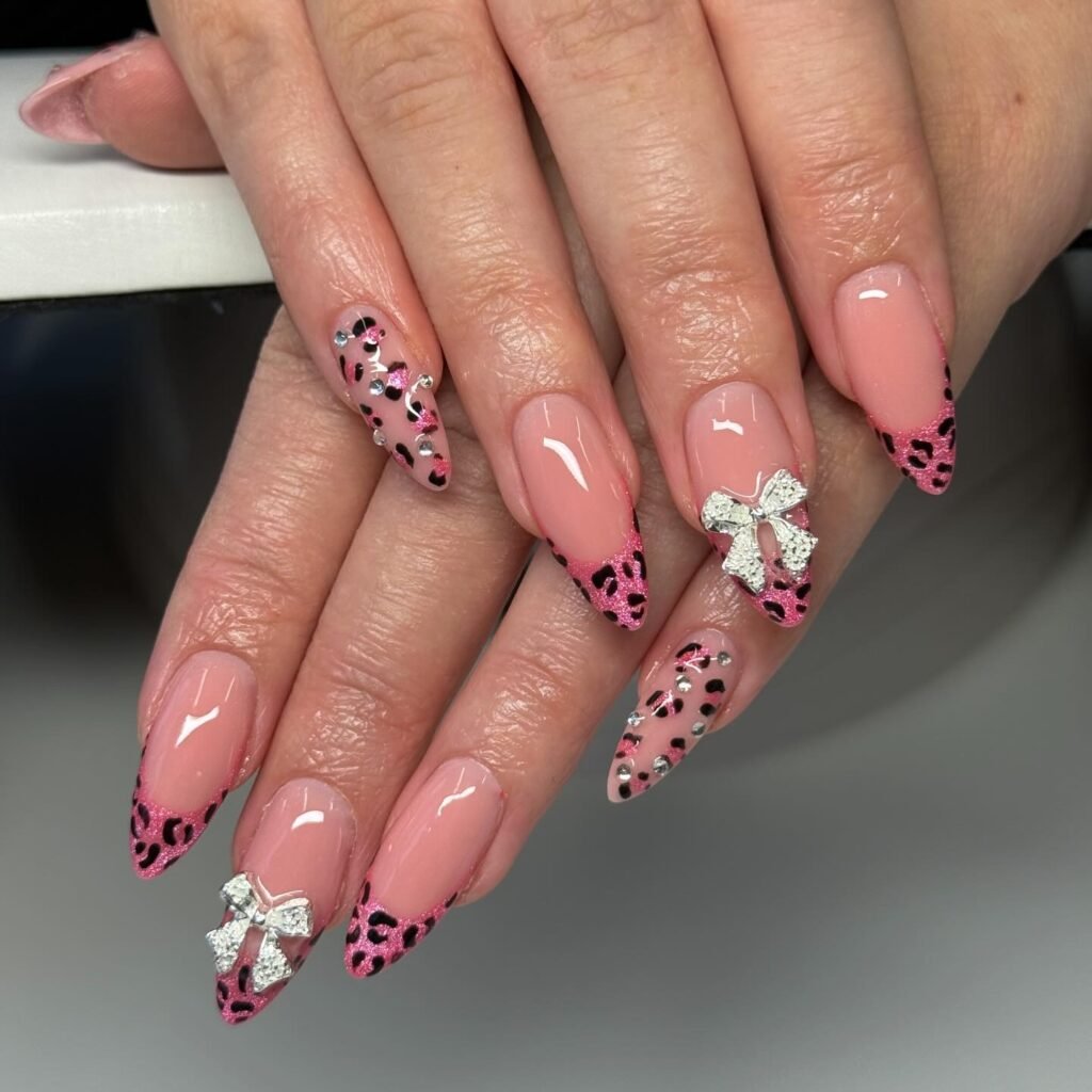 Pink leopard print nails with rhinestones and silver bows, featuring a stylish and trendy nail art design.