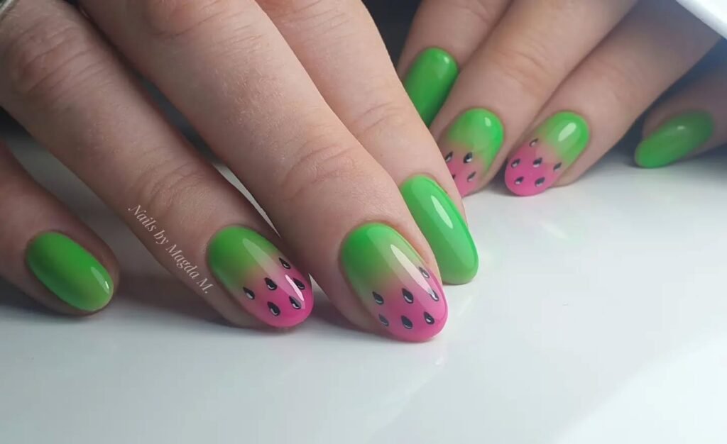 Watermelon-themed nail art with green tips and pink base featuring black seeds, showcasing a creative and playful manicure.