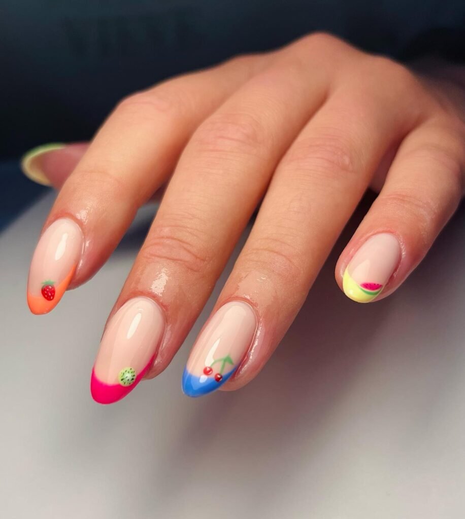 Colorful fruit-themed nail art with strawberry, kiwi, cherry, and watermelon decorations on manicured fingers.