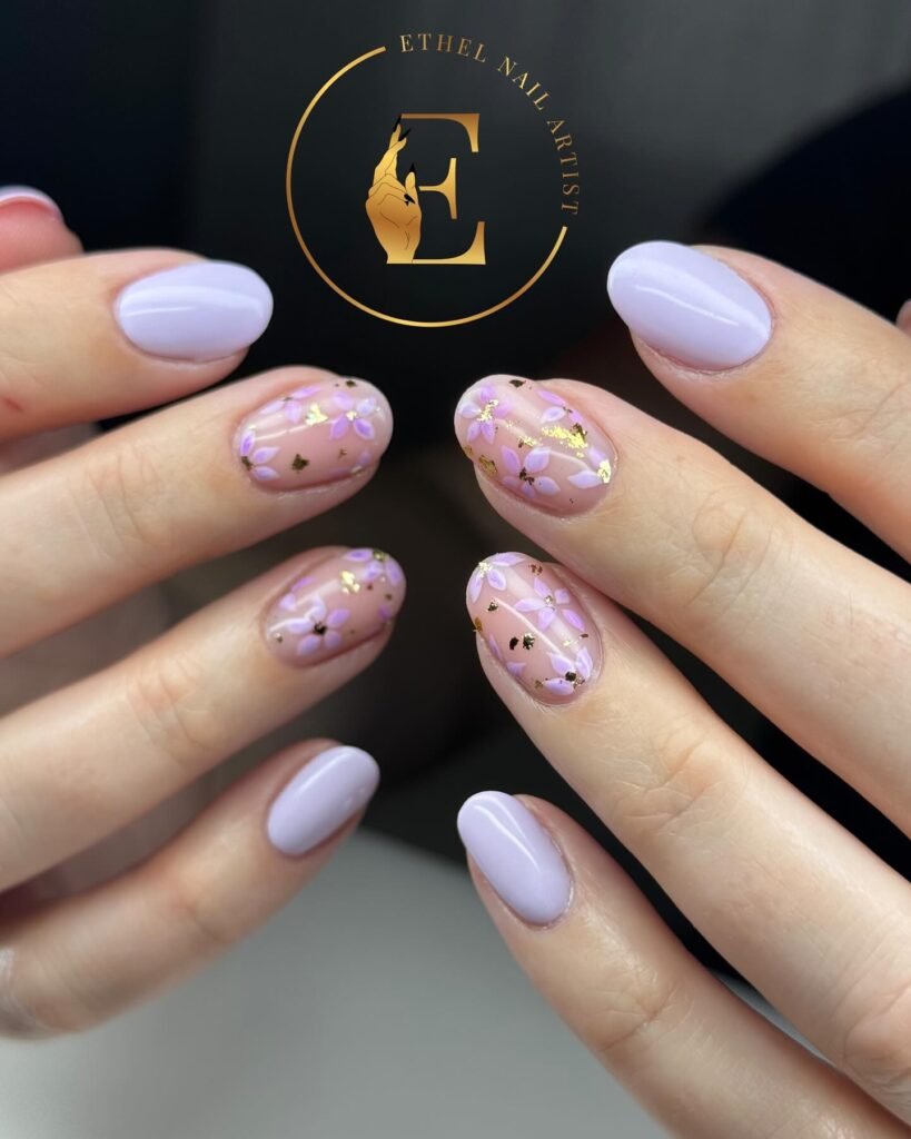 Lavender and floral nail art with gold accents on oval-shaped nails. Elegant manicure design.