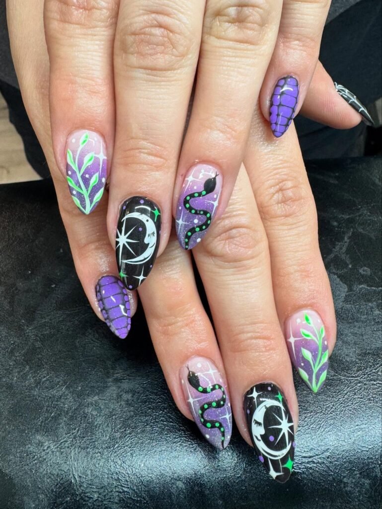 Colorful nail art with celestial and snake designs in black, purple, and green on a black background.