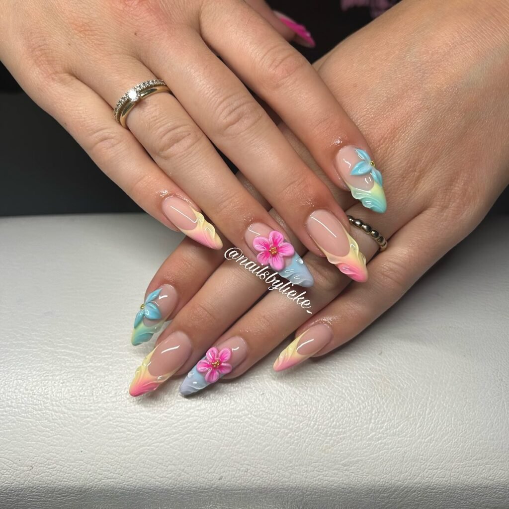 Colorful floral nail art with 3D flowers on manicured hands, featuring pastel and gradient designs.