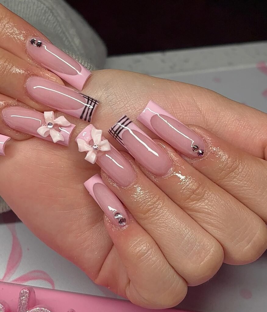 Pink coffin nails with bows, stripes, and rhinestones, in a glossy elegant manicure design.