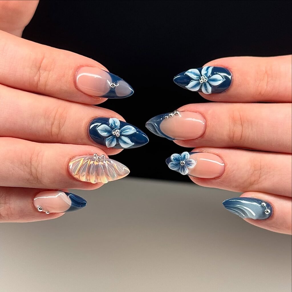 Stylish blue and floral nail art with 3D accents and glossy finish on well-manicured hands.
