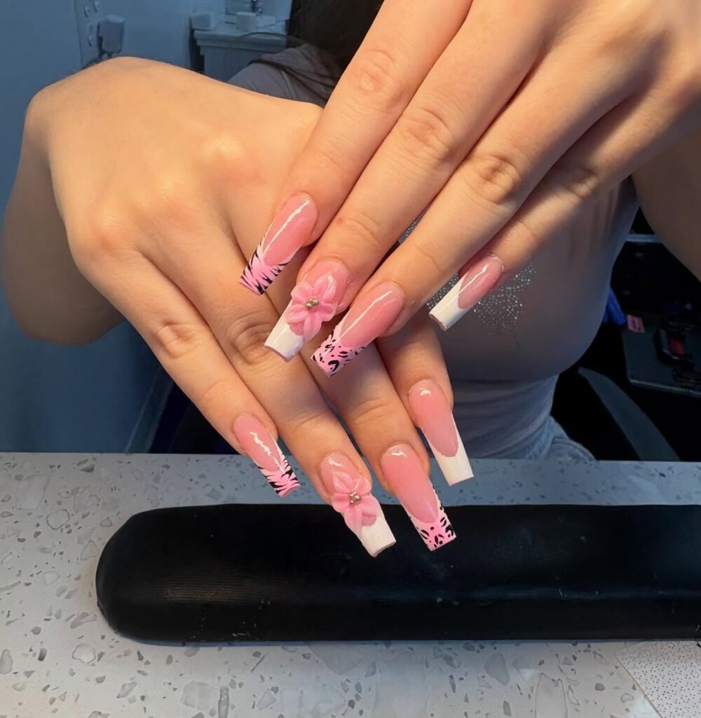 Elegant pink and white acrylic nails with floral design, showcasing intricate nail art and style.