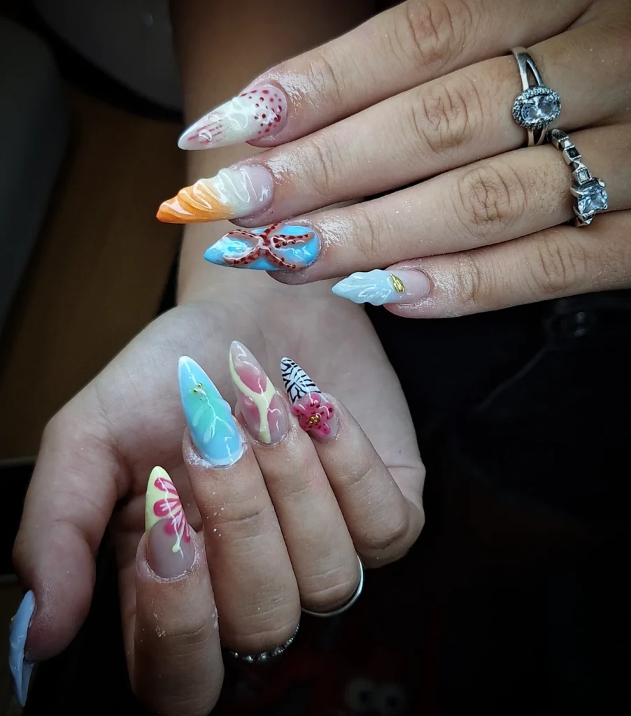 Colorful and intricate nail art with floral and abstract designs on stiletto-shaped nails.