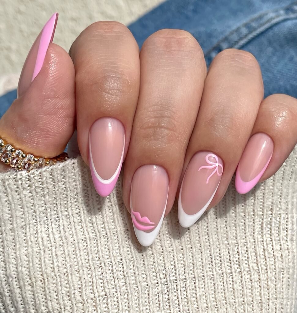 Stylish pink and white French manicure with bow and lips design on almond-shaped nails.