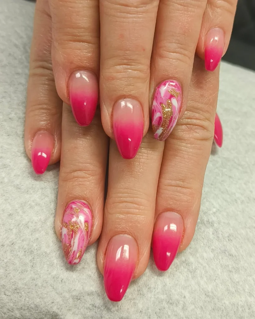 Pink gradient almond nails with marble and gold accents on two fingers, set against a soft background.