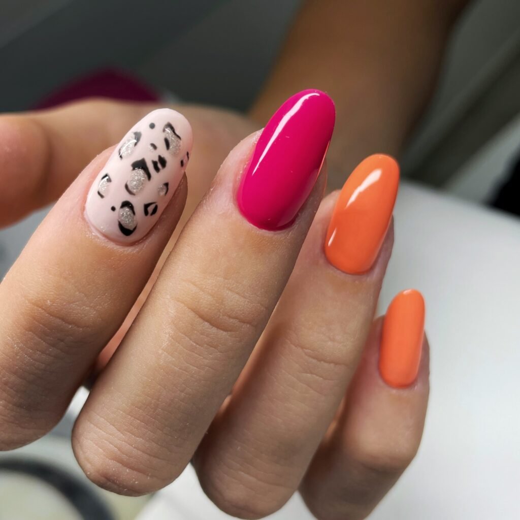 Colorful nail art with pink, orange, and leopard print design on four manicured nails.