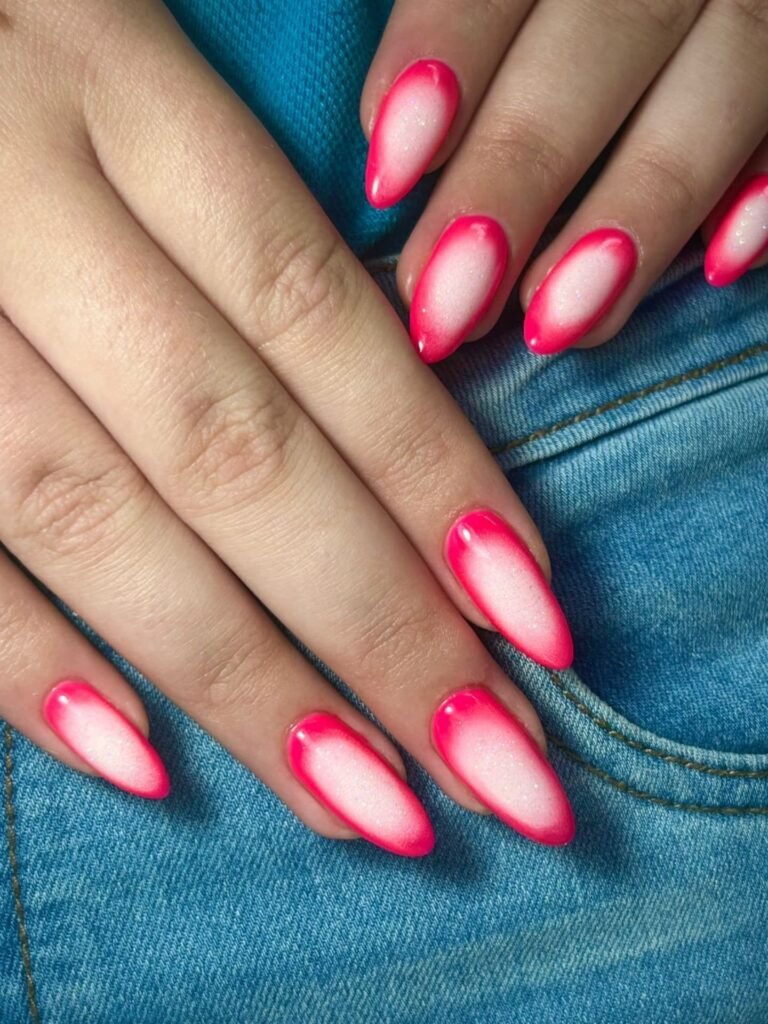 Hands with gradient pink and white nails on denim fabric background. Fashionable manicure style.