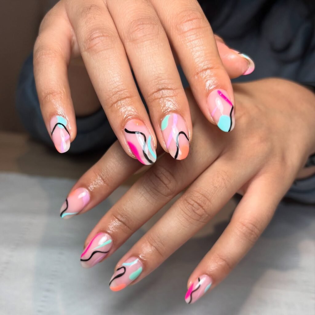 Colorful abstract nail art with pink, blue, and black swirls on manicured hands.