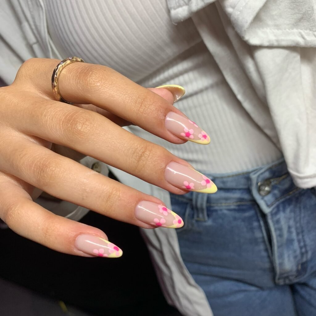 Elegant nails with yellow-tipped French manicure and pink flower design.