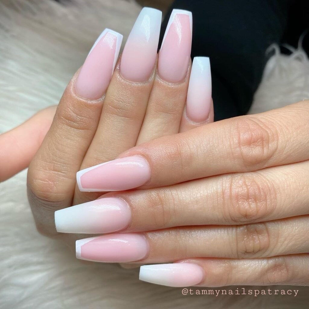 Pink ombre coffin nails on a woman's hands, showcasing trendy and elegant nail art design.