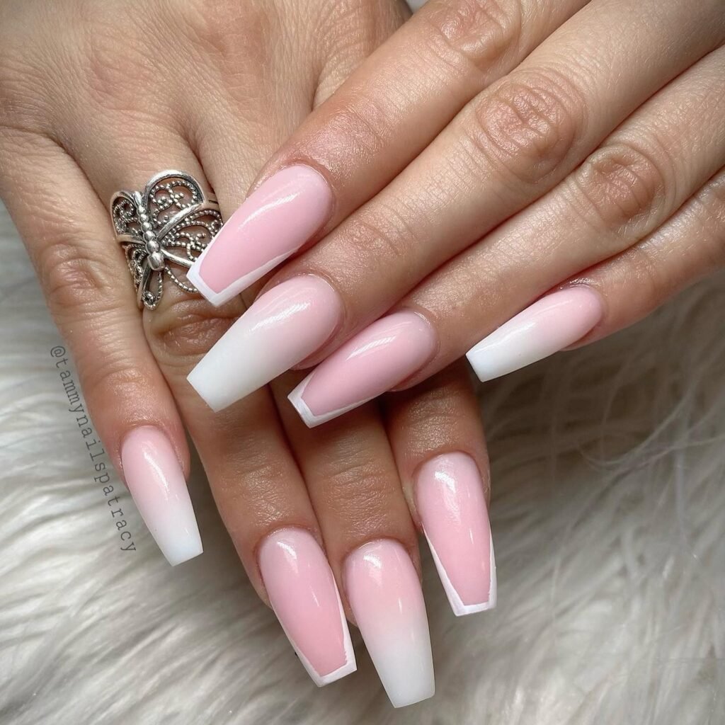 Elegant pink and white ombre coffin nails with a silver butterfly ring on a fluffy background.
