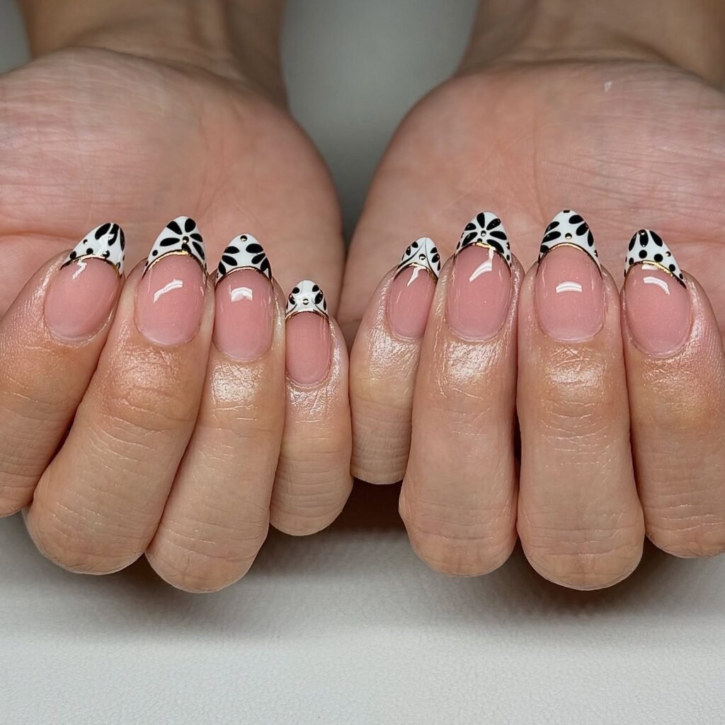 Stylish nails with black and white floral French tips on a neutral base. Modern manicure design.