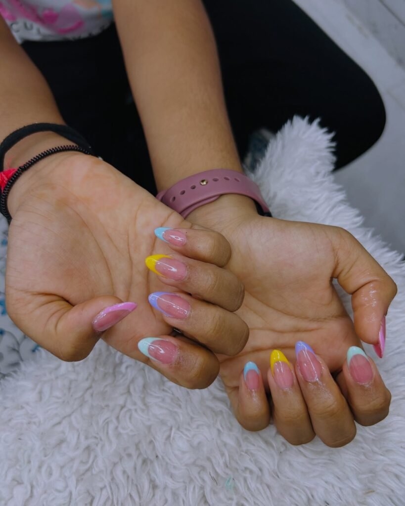 Colorful pastel manicure on almond-shaped nails with a cozy background.