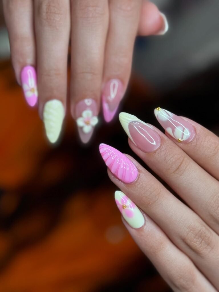 Elegant pink acrylic nails with floral designs and gold accents. Perfect for stylish and trendy nail art inspiration.