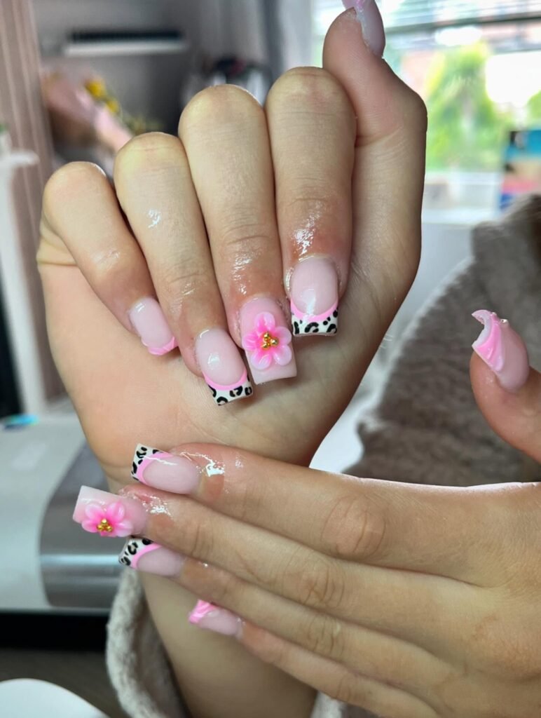 Pink floral and leopard print nails with 3D flower detail on manicured hands.