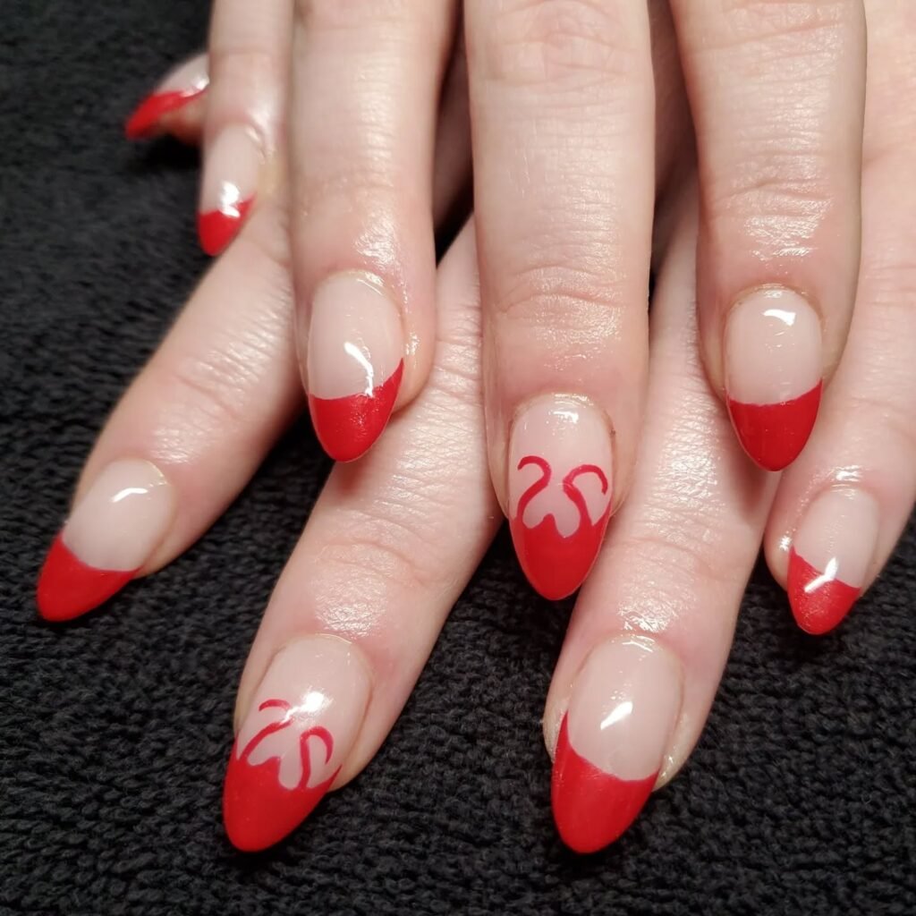 Red French tip nails with heart designs on a black background. Elegant manicure showcasing creative nail art.