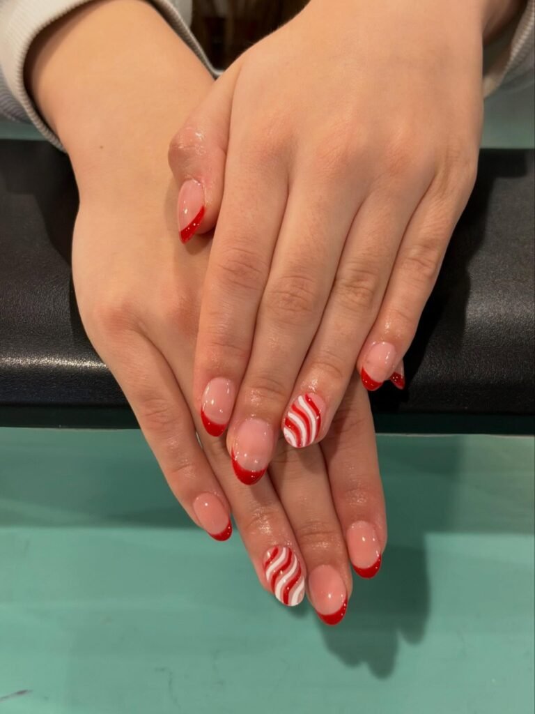 Red and white wavy nail design with red French tips on neatly manicured hands.