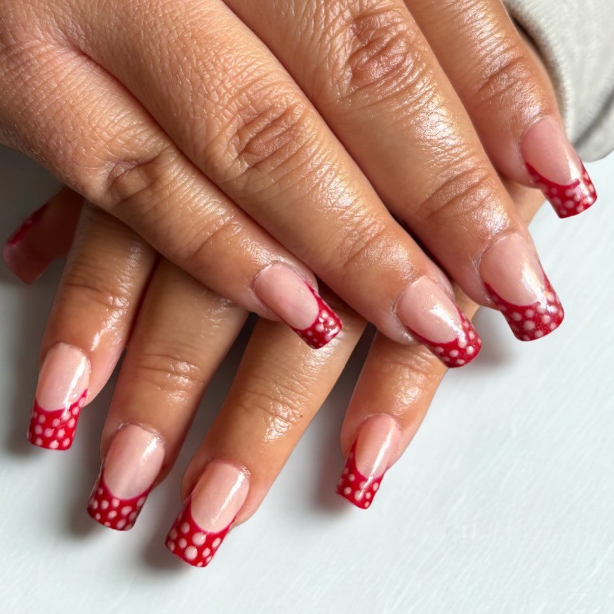 Red polka dot French manicure on square-shaped nails, adding a vibrant touch to the well-groomed hands.