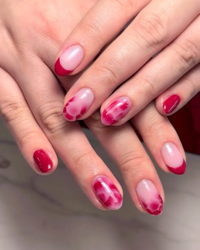 Stylish red and pink marble nail art on manicured hands showcasing creative fashion and beauty design.