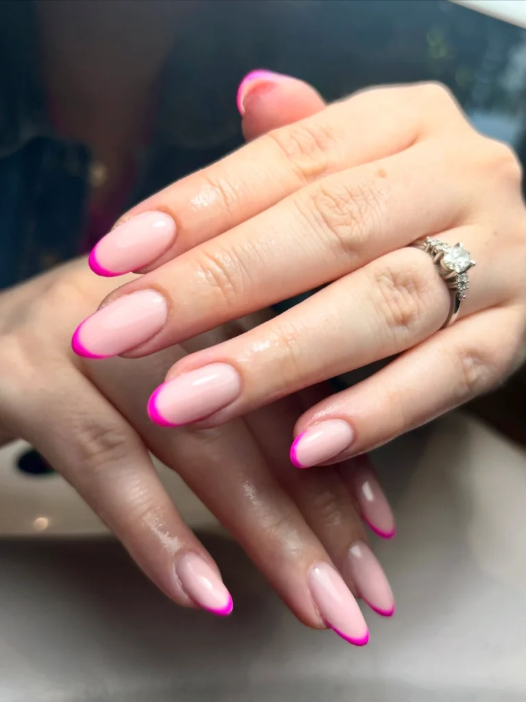 Close-up of hands with pink French manicure and an elegant diamond ring, showcasing chic nail art design.
