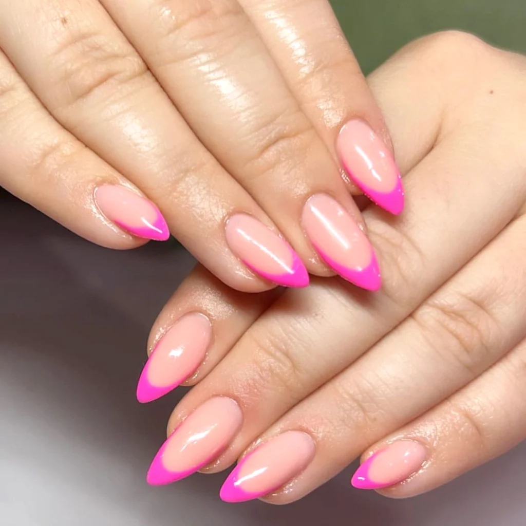 Close-up of hands with glossy pink almond-shaped nails featuring vibrant hot pink French tips.