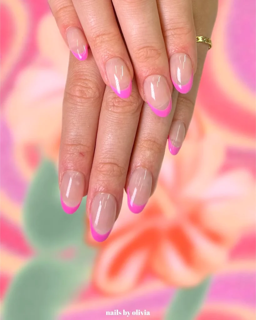 Hands with pink French manicure on a colorful floral background.