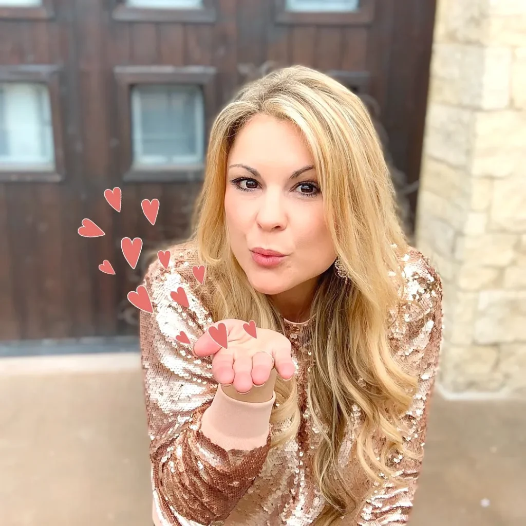 Woman in sparkly outfit blowing a kiss with heart illustrations, standing outdoors.