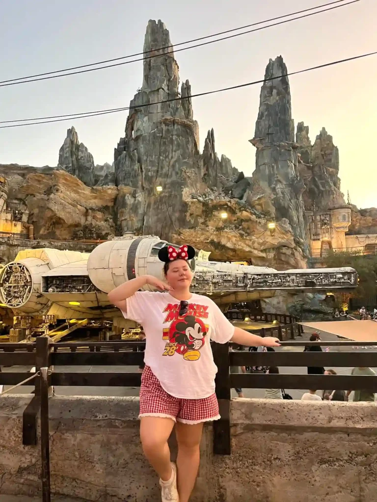 Person posing in Mickey Mouse attire at Star Wars: Galaxy's Edge, Disneyland with Millennium Falcon backdrop.