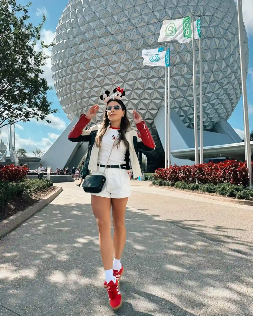 Woman with Minnie Mouse ears posing at Epcot Center, Disney World, with iconic geosphere in background.