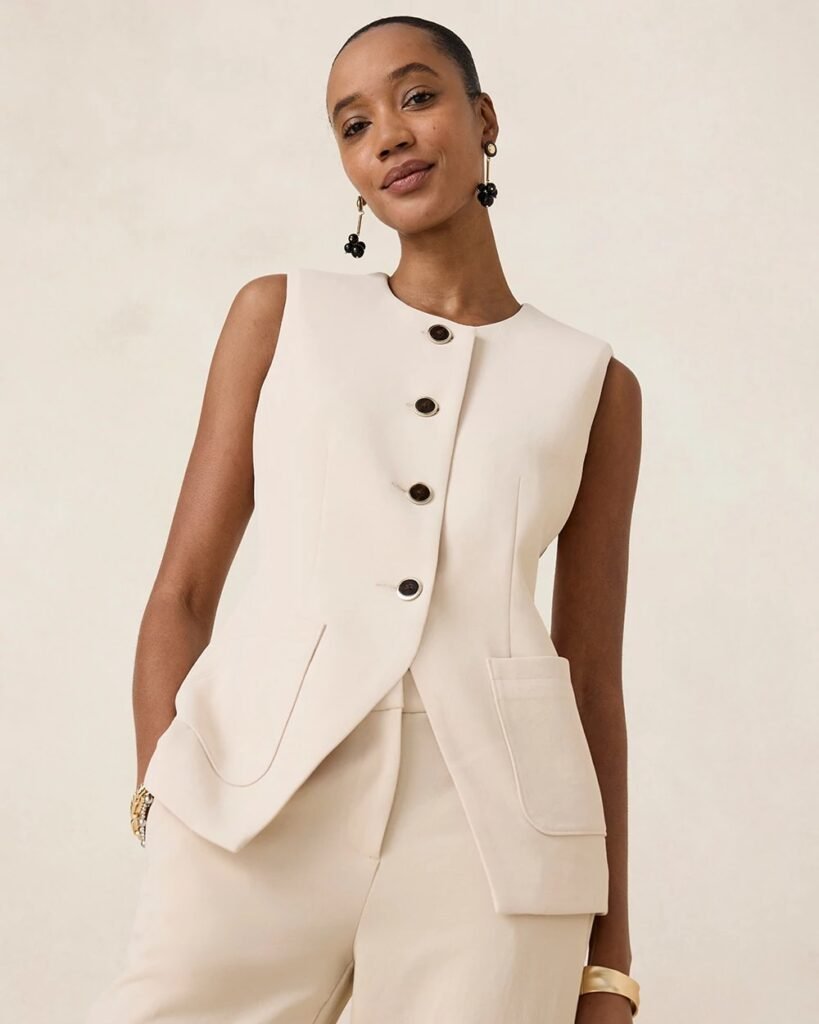 Elegant woman modeling a sleeveless beige vest with buttons and pockets, styled with chic accessories against a neutral backdrop.